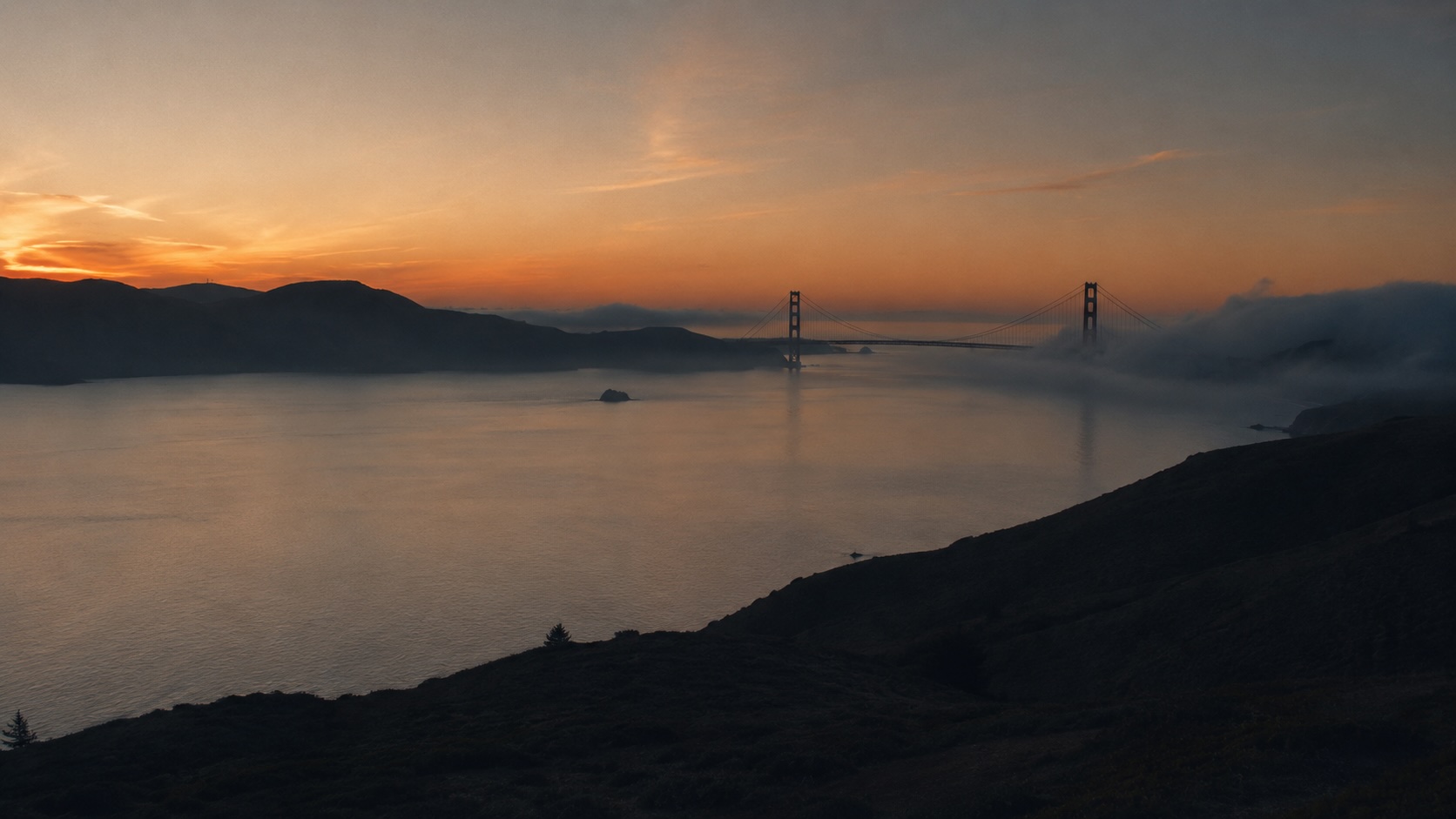 San Francisco Bay Bridge at dusk, the Bay Area skyline reflected in the water
